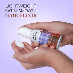 Hair serum pump bottle held in hands, purple label with herbal design