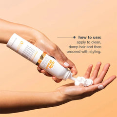 Hair treatment bottle squeezed onto hands, white bottle with orange label