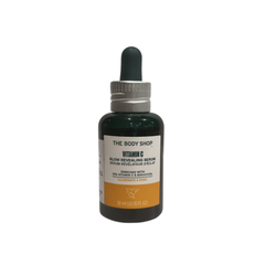 The Body Shop Vitamin C glow serum in dark green glass bottle with dropper