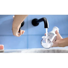 Power flosser stream near sink faucet with hands and flosser nozzle