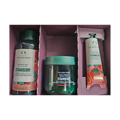 Strawberry essentials gift set with shower gel, body scrub jar, and hand cream tube.