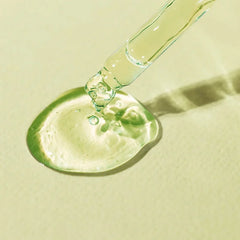 Amber serum drop from a dropper, glossy and viscous on a pale surface