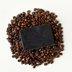 Dark coffee bathing bar soap resting on a pile of coffee beans