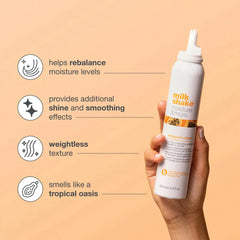 Whipped cream hair treatment bottle held in hand, white with orange label