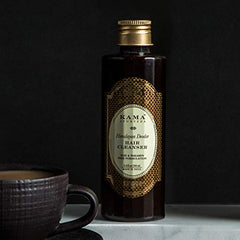 Kama Ayurveda Himalayan Deodar Hair Cleanser bottle with gold cap, next to mug