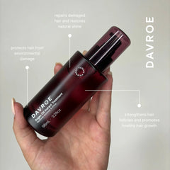 Argan oil instant treatment spray bottle in hand, burgundy and black