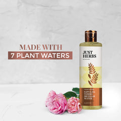 Just Herbs toner + micellar water bottle, olive glass and gold cap beside roses