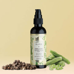 Organic moringa oil bottle with pump, beside green moringa leaves and seed pods
