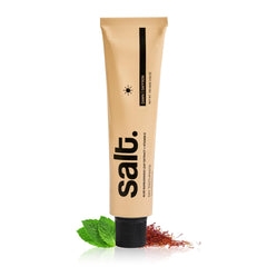 Toothpaste tube with black cap, beige-gold body, salt branding.