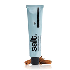 Toothpaste tube, light blue with black cap, with cinnamon sticks and reflection