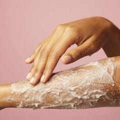Body scrub being rubbed on skin with creamy white exfoliating flakes