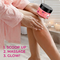 Pink body scrub jar with black lid while hands massage scrub into legs.