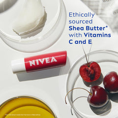 Red NIVEA lip balm stick with white label and small jar beside cherries