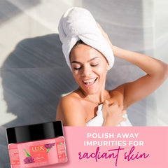Pink body scrub jar with black lid near a person drying hair and applying scrub.