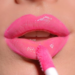 Pink lip gloss swiped on lips with applicator brush, glossy shine