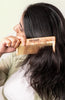Neem wood fine-tooth hair comb held to long dark hair