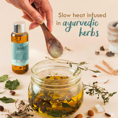 Hair and scalp oil bottle with amber liquid, shown with herb-infused jar