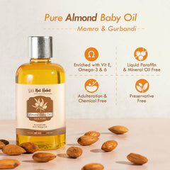 Almond baby oil bottle with silver cap and scattered almonds, amber-gold oil