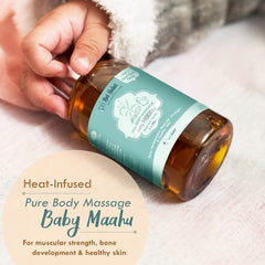 Hand holding a baby massage oil bottle with teal label and amber liquid