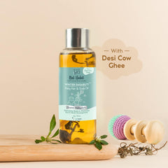 Baby hair and scalp oil bottle with amber liquid, teal label, metal cap