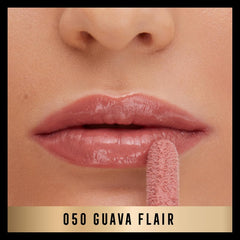 Glossy pink coral lip glaze on lips with applicator tip