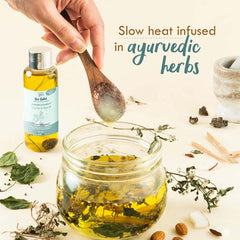 Baby hair and scalp oil bottle with spoonful of herb-infused yellow oil from a jar.