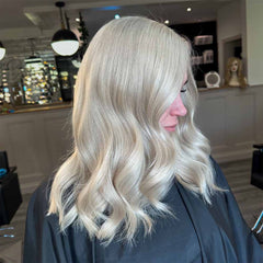 Platinum-silver wavy hair on a person, side view after toning