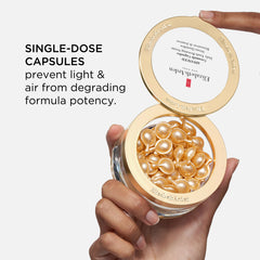 Hand holding open ceramide capsule container with gold capsules inside