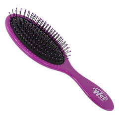 Purple detangling hair brush with black bristles on curved pad, angled view