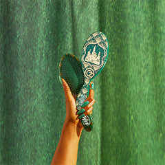Green patterned detangling hair brush with handle held in a hand