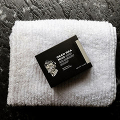 Soap bar with Dead Sea Mud and Bilberry label on white towel