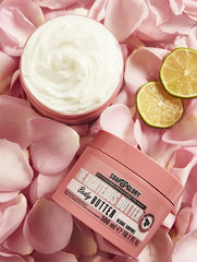 Body butter jar with pale cream swirl, citrus slices, and rose petals