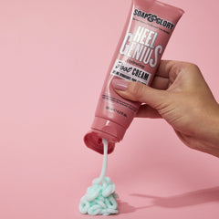 Hand squeezing pink foot cream from Soap & Glory Heel Genius tube