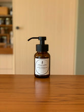 Foaming soap dispenser bottle with amber liquid and black pump, botanical label