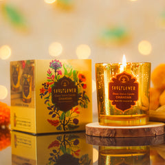 Glass votive candle in amber gold glitter jar with flame and decorative CHANDAN label