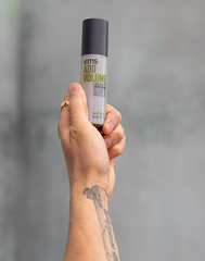 KMS Add Volume Liquid Dust bottle held in hand, dark cap and green label