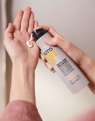 KMS Curl Up Control Crème bottle held in hands, dark flip cap, 150 ml