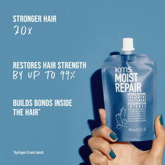 KMS Moist Repair hair treatment pouch in hand, blue with white flip-top cap.