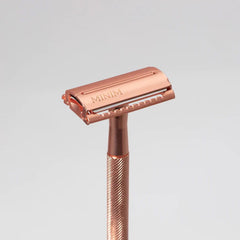 Rose-gold safety razor with MINIM logo on cartridge head and textured grip handle