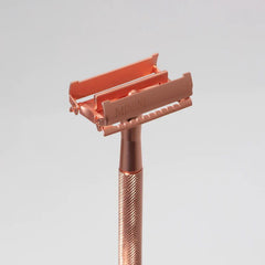 Rose-gold safety razor with open double-edge blade head and textured handle