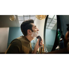 Electric shaver in use on face, three rotating foil heads, wet & dry design.