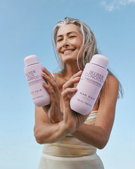 Hair care shampoo and conditioner bottles held by smiling blonde woman