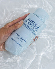 Hydrate shampoo bottle in hand with smooth & restore moisture balance label