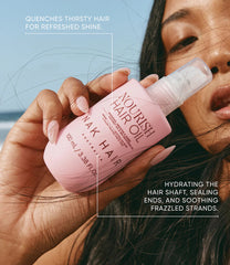 NAK Nourish Hair Oil 100 ml bottle held near hair on a woman