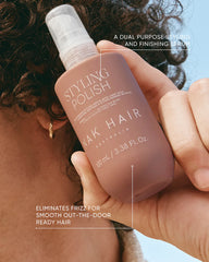 Brown styling polish serum bottle held in hand with white pump applicator.