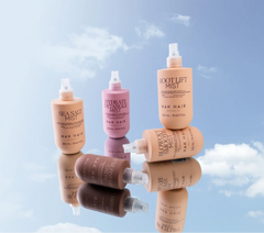 Assorted hair mist bottles with white pump nozzles, including a peach root lift bottle