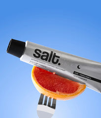 Toothpaste tube, silver metal with black nozzle cap, Salt; close to grapefruit slice