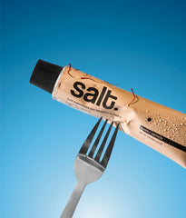 Beige-gold salt toothpaste tube with black cap, angled view.