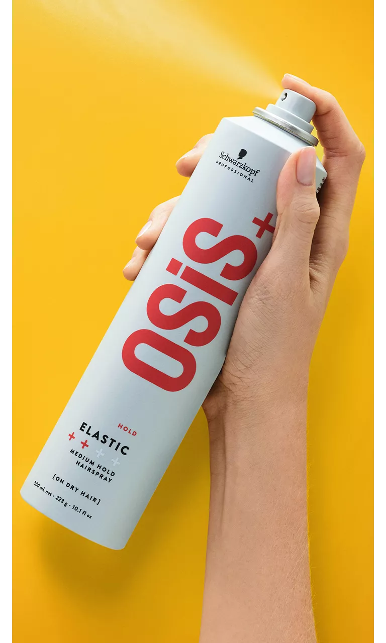 Elastic hairspray bottle with grey cap, held in hand