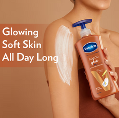 Vaseline cocoa glow serum-in-lotion bottle held near bare shoulders with white lotion